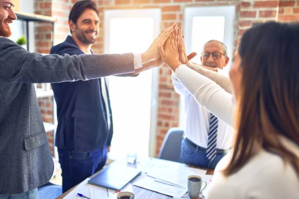 istock Group of business workers standing with hands together at the office 1204809144