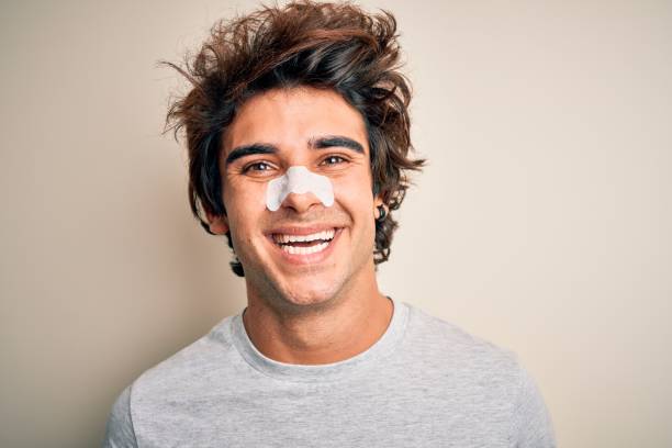 istock Young handsome man using nose strip standing over isolated white background with a happy and cool smile on face. Lucky person. 1204811594