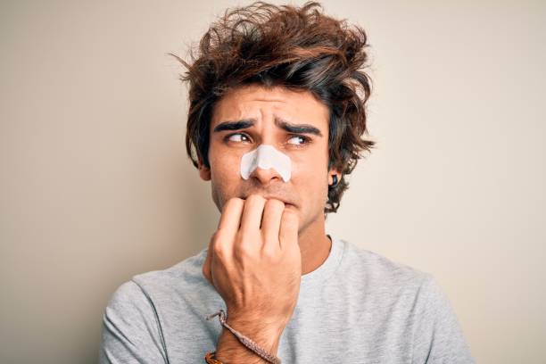 istock Young handsome man using nose strip standing over isolated white background looking stressed and nervous with hands on mouth biting nails. Anxiety problem. 1204811595