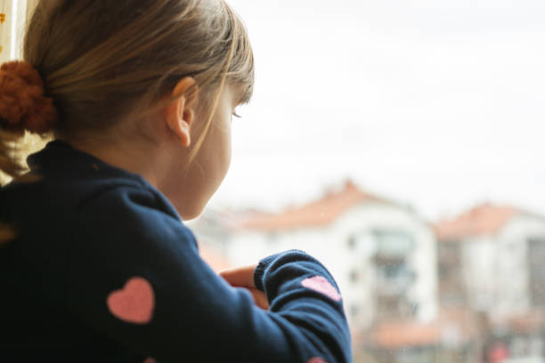 istock Beautiful little girl looking out the window 1204811665