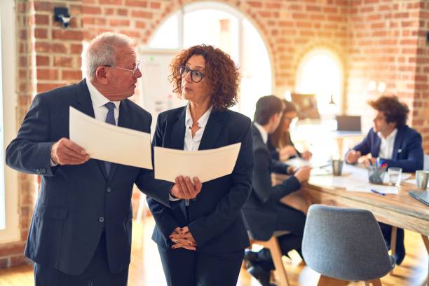 istock Two business workers working together. Speaking and reading documents standing at the office 1204811920