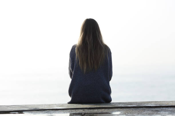 Back view of a woman looking at horizon on a ledge