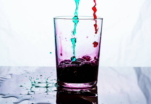 istock A glass being filled by pink and green liquid. White background. 1204821488