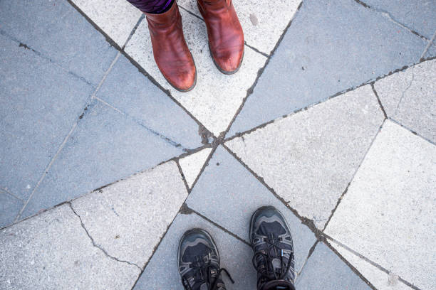 Two pairs of feet standing on stone slabs.