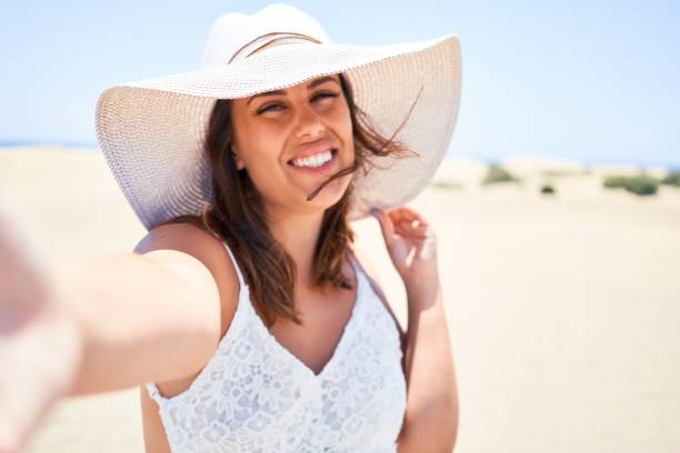istock Young beautiful woman smiling happy taking a selfie using smartphone at maspalomas dunes beach 1204821532