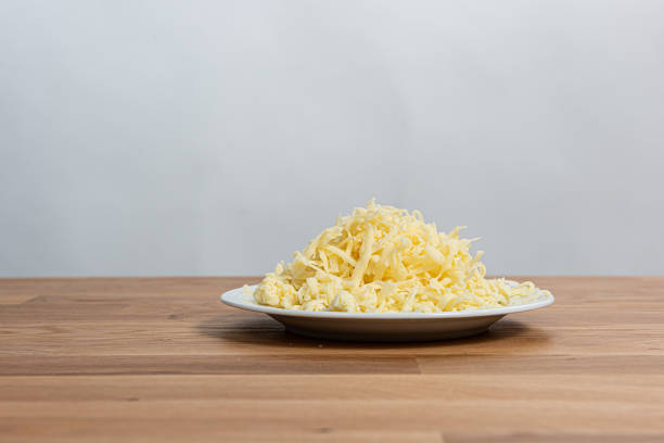 Plate of finely grated cheese on a wooden table. Plate of finely grated cheese on a wooden table. finely stock pictures, royalty-free photos & images