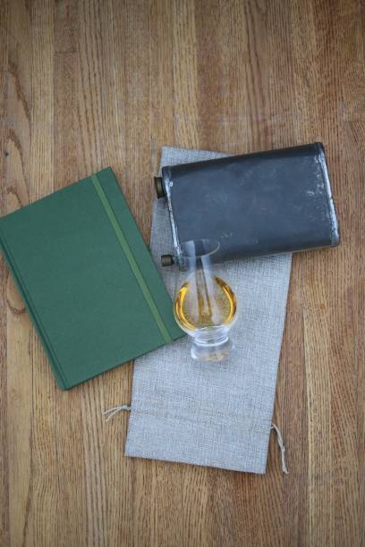 istock Whisky glass on a notebook flask and burlap with wood background 1204828135