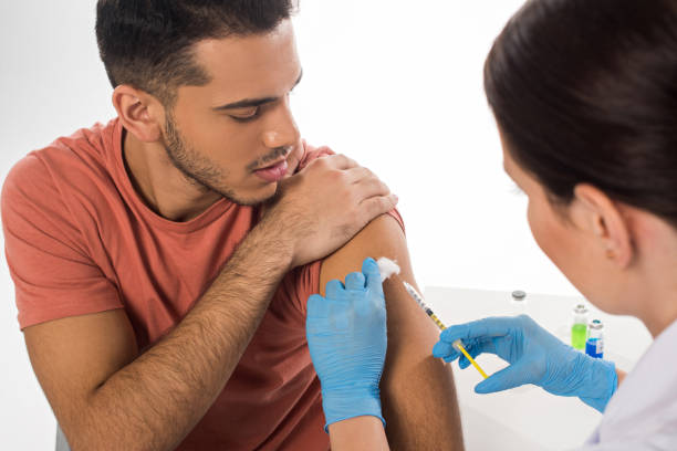 istock Selective focus of doctor doing injection to handsome patient isolated on white 1204828144