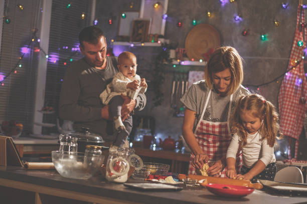 istock Two parents with their kids baking cookies in modern domestic kitchen 1204829900