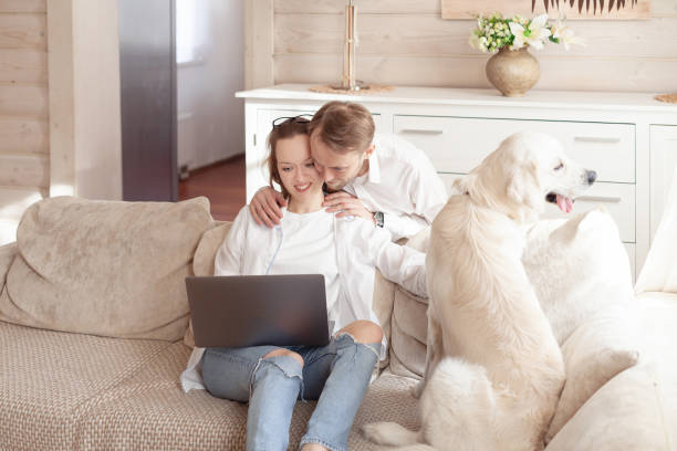 istock Young married couple using a laptop next to their beloved dog 1204834571