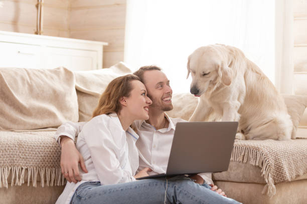 istock Young married couple using a laptop next to their beloved dog 1204837126