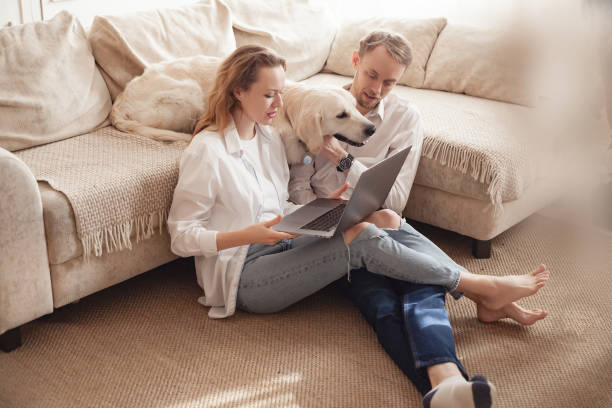 istock Young married couple using a laptop next to their beloved dog 1204837163