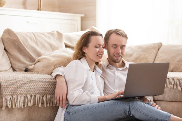 istock Young married couple using a laptop next to their beloved dog 1204837190