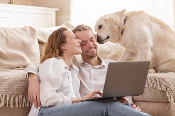 istock Young married couple using a laptop next to their beloved dog 1204837225