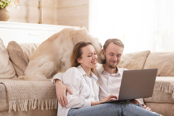 istock Young married couple using a laptop next to their beloved dog 1204837254