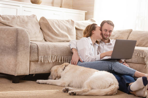 istock Young married couple using a laptop next to their beloved dog 1204837489