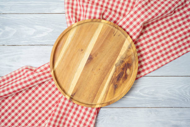 istock Round wooden tray with red checked tablecloth on rustic wooden table Kitchen, cooking or baking mock up background for design. 1204841077