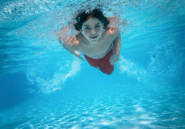 Portrait of a cute little boy swimming in the pool with copy space