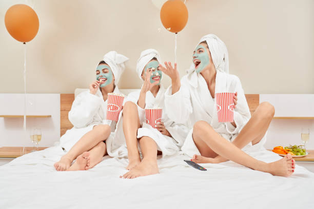 istock Girls eating popcorn in bed, having fun. 1204844343