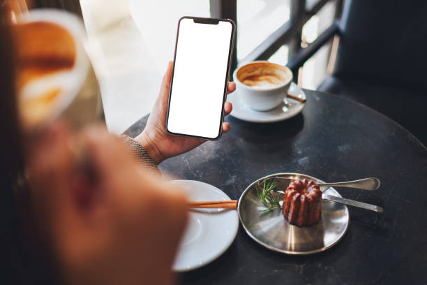 istock a woman holding black mobile phone with blank desktop screen while drinking coffee in cafe 1204844360