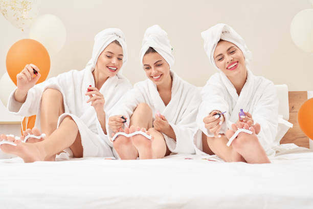 istock Smiling girls in bathrobes doing pedicure. 1204844677