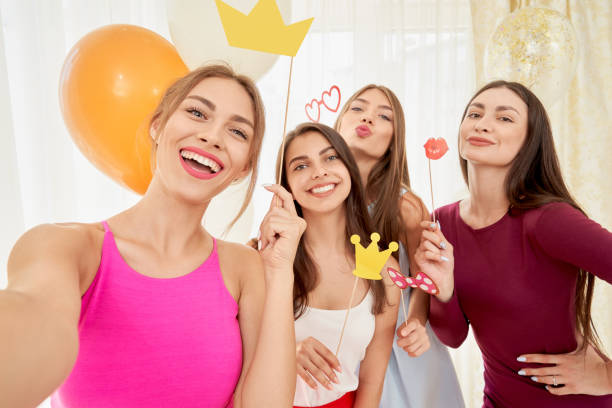 istock Smiling girlfriends taking selfie with paper accessories. 1204846809