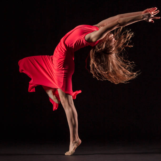 istock Dancer in red dress on black background 1204847140