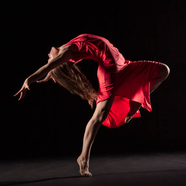 istock Dancer in red dress on black background 1204847241