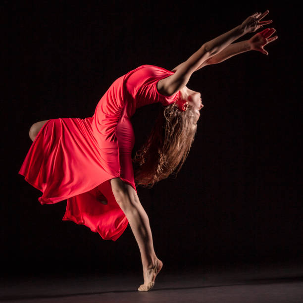 istock Dancer in red dress on black background 1204847332