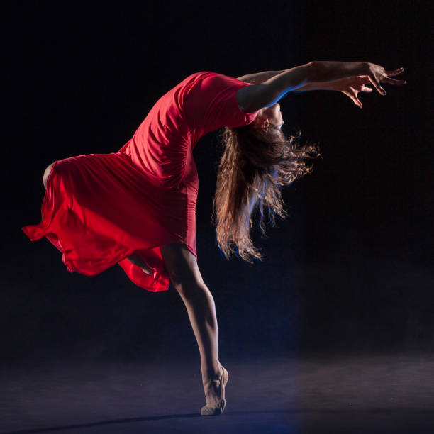istock Dancer in red dress on black background 1204847389
