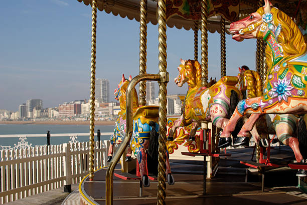 Merry-go-round at Brighton Pier in East Sussex, England Traditional fairground roundabout with painted horses on Brighton Pier. East Sussex. England hurdy gurdy stock pictures, royalty-free photos & images