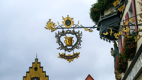 Rothenburg ob der Tauber, Germany - October 10, 2019: Looking up at the historic signboard of the famous Marien Apotheke on the Market Square, half-timbered buildings and old gables, copy space.