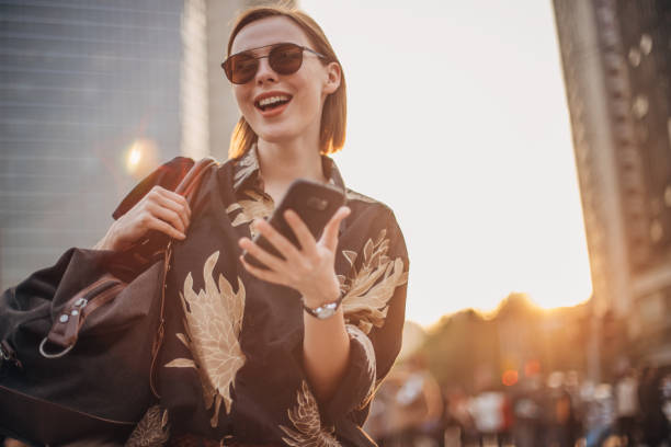 istock Stylish young woman with sunglasses is text messaging 1204852052