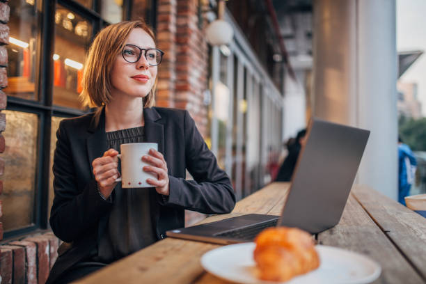 Young woman is having coffee and using laptop