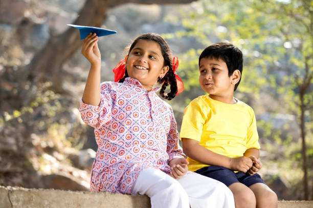 istock Boy and girl playing with paper airplane 1204853235