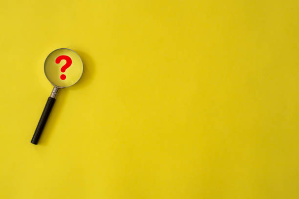 Question Mark on magnifying glass with yellow background stock photo