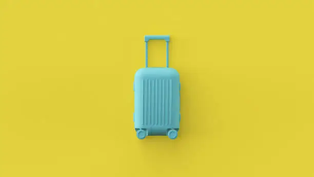 Photo of Blue luggage bag, cabin baggage on yellow background, traveling summer concept. Stylish vacation suitcase, pastel colors, summertime tourist background with space for text. Tourism conceptual design.
