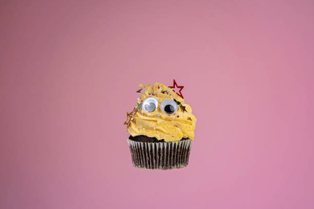 lustige schokolade muffin mit gelben vereisung - back to front ideas surrealism concepts stock-fotos und bilder