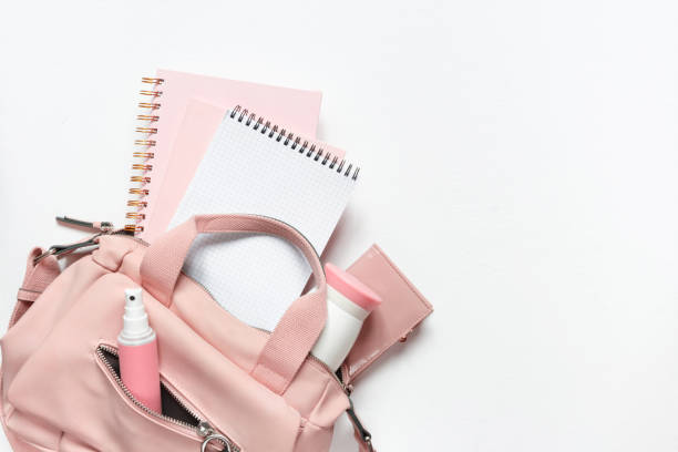 Flat lay, Women's accessories pink backpack, glider, water bottle and spray for the face on a white background, trend things girl generation z, fashion background