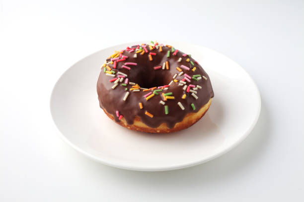 istock chocolate frosted doughnut on plate isolated on white background 1204861539