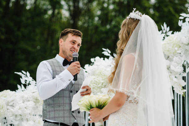 istock Happy bride and groom exchanging wedding vows on ceremony under the arch on the backyard banquet area. The groom says the promise in the microphone. Fidelity in love. 1204862651