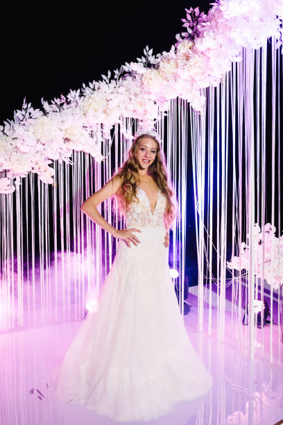 istock Bride near arch. Night ceremony with colored light. Wedding under the arch decorated with flowers of the outdoor. 1204862803