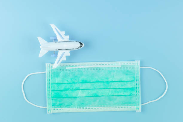 소설 코로나 바이러스 (2019-ncov) 또는 우한 코로나 바이러스와 인플루엔자에 대한 파란색 배경에 보호 얼굴 마스크 및 비행기 모델. 방부제, 위생 및 건강 관리 개념 - tranfer 뉴스 사진 이미지