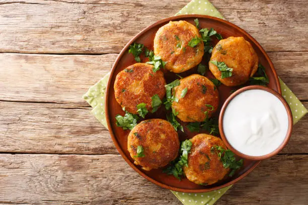 Indian potato patties Aloo Tikki served with yogurt close up in a dish on the table. Horizontal top view from above