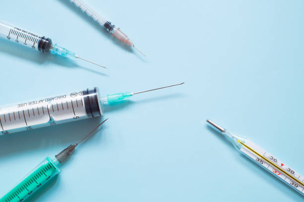 istock Medical syringes and a thermometer on blue background. 1204866870