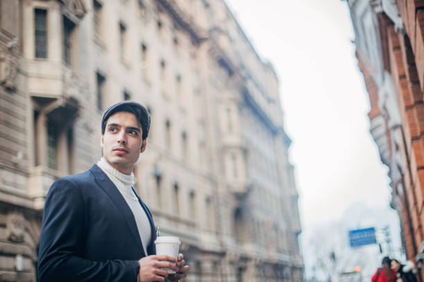 istock Handsome guy is drinking coffee on the street 1204868465