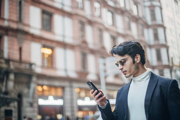 istock Elegant man is text messaging on the street 1204868529