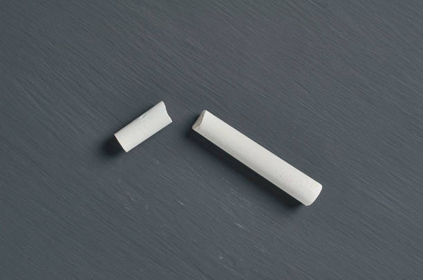 istock One white broken piece of chalk on black chalkboard. Flat lay. Close-up 1204871807