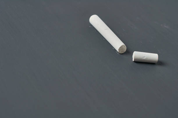 istock One white broken piece of chalk on black chalkboard. Copy space 1204871815