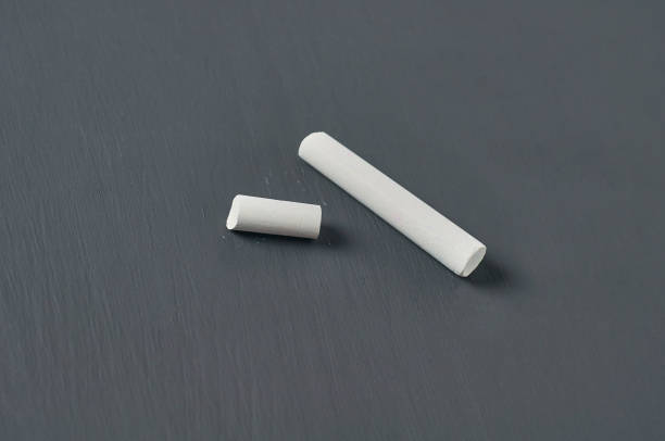 istock One white broken piece of chalk on black chalkboard. Close-up 1204871866